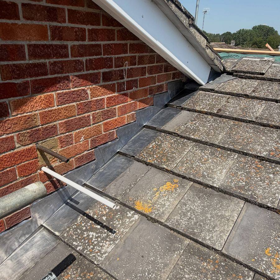 Slate roof repair at a brick abutment
