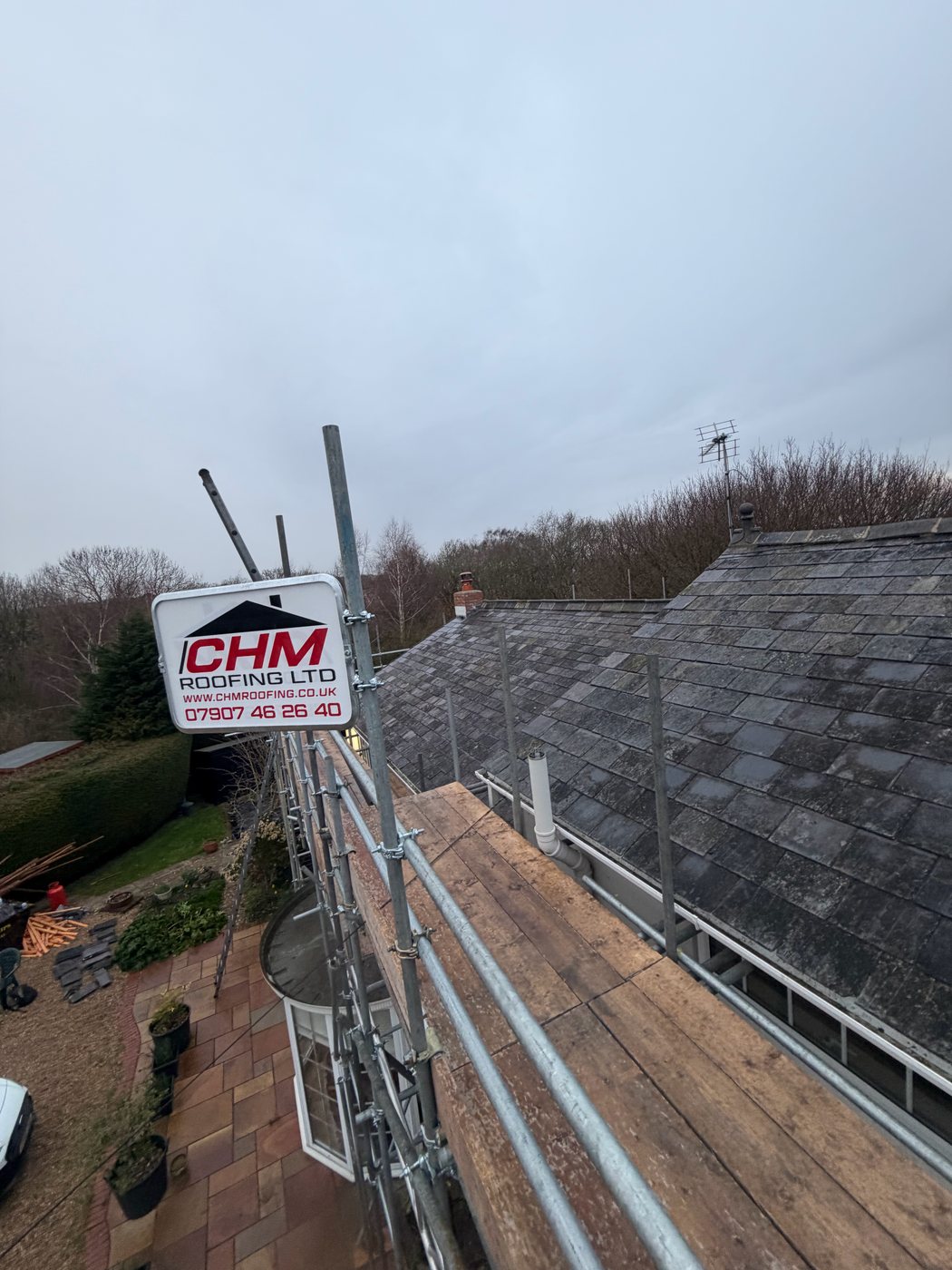 CHM Roofing scaffolding overlooking a slate roof and patio during a re-roof job